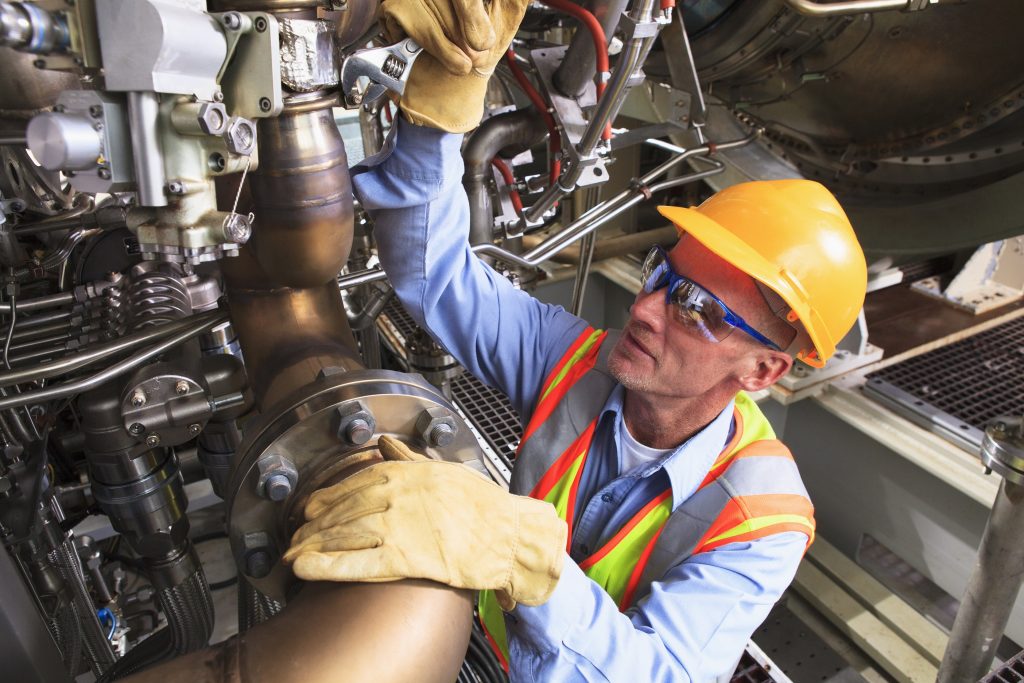 Engineer at turbine stage of gas turbine which drives generators in power plant while turbine is powered down